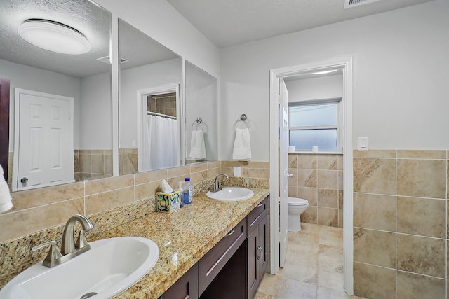 bathroom featuring tile walls, toilet, and vanity