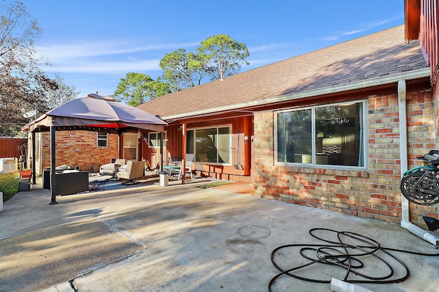 rear view of property featuring a gazebo, a patio area, and an outdoor living space