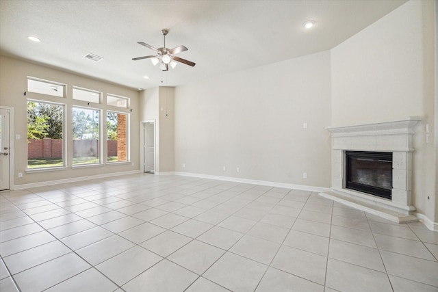 unfurnished living room with ceiling fan, a tiled fireplace, and light tile patterned flooring