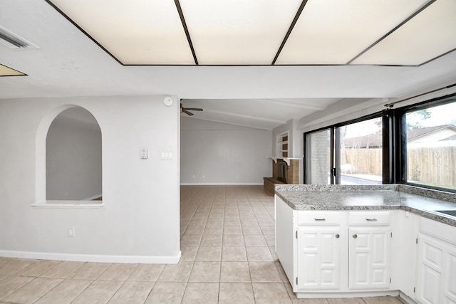 kitchen featuring lofted ceiling, ceiling fan, light tile patterned floors, and white cabinetry