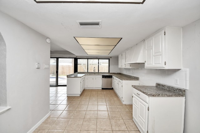 kitchen featuring white cabinets, dishwasher, light tile patterned flooring, custom range hood, and backsplash