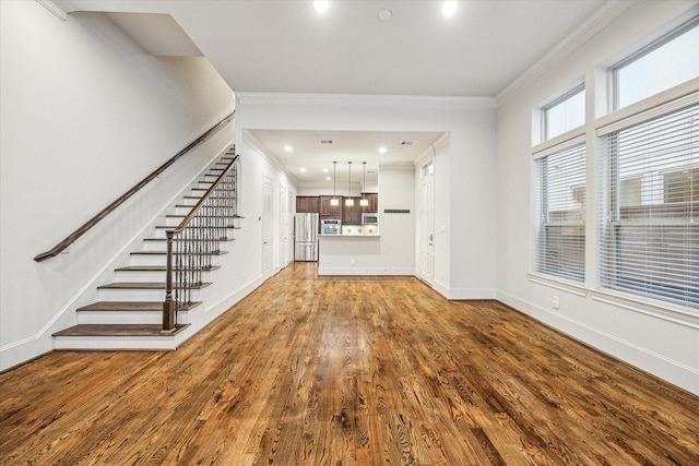 unfurnished living room featuring hardwood / wood-style flooring and crown molding