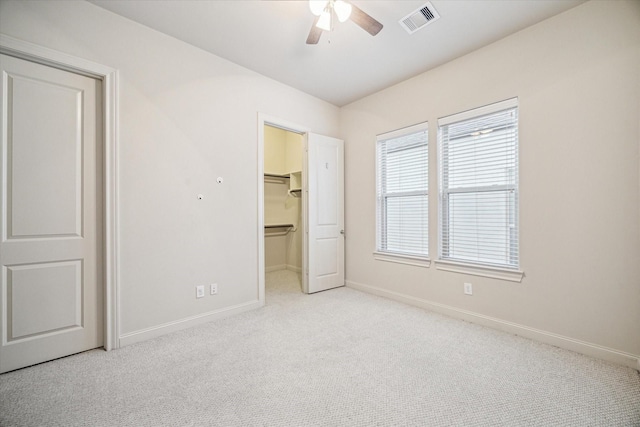 unfurnished bedroom with light colored carpet, ceiling fan, a spacious closet, and a closet