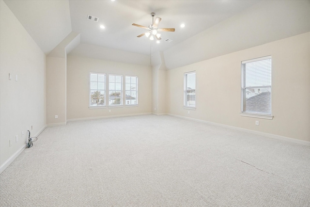 empty room featuring lofted ceiling, light carpet, ceiling fan, and a wealth of natural light