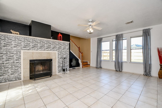 unfurnished living room with a fireplace, ceiling fan, and light tile patterned floors