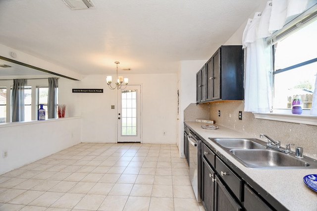 kitchen with stainless steel dishwasher, hanging light fixtures, a notable chandelier, light tile patterned floors, and sink