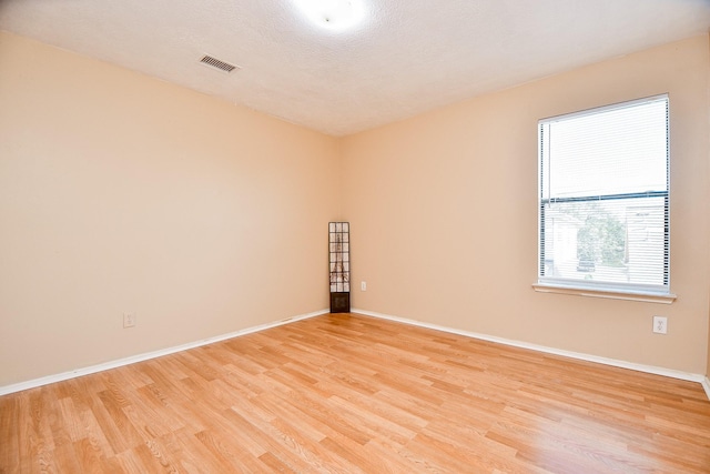 unfurnished room with a textured ceiling and light hardwood / wood-style floors