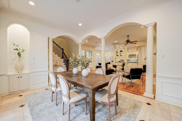 tiled dining space with ceiling fan and crown molding