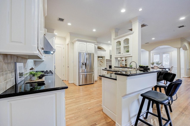 kitchen featuring kitchen peninsula, stainless steel fridge with ice dispenser, decorative backsplash, and white cabinetry