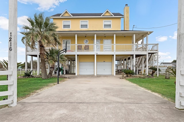 raised beach house with covered porch, a front lawn, and a garage