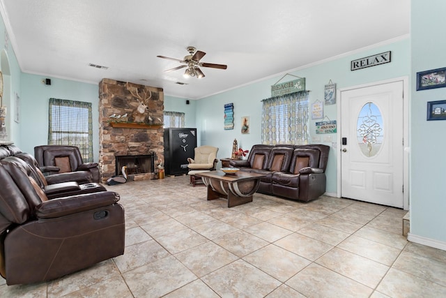 tiled living room with ornamental molding, ceiling fan, and a stone fireplace