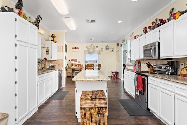 kitchen featuring stainless steel appliances, decorative backsplash, a center island, and white cabinetry