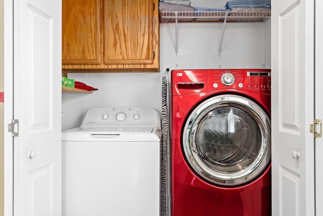 laundry area featuring washing machine and clothes dryer and cabinets