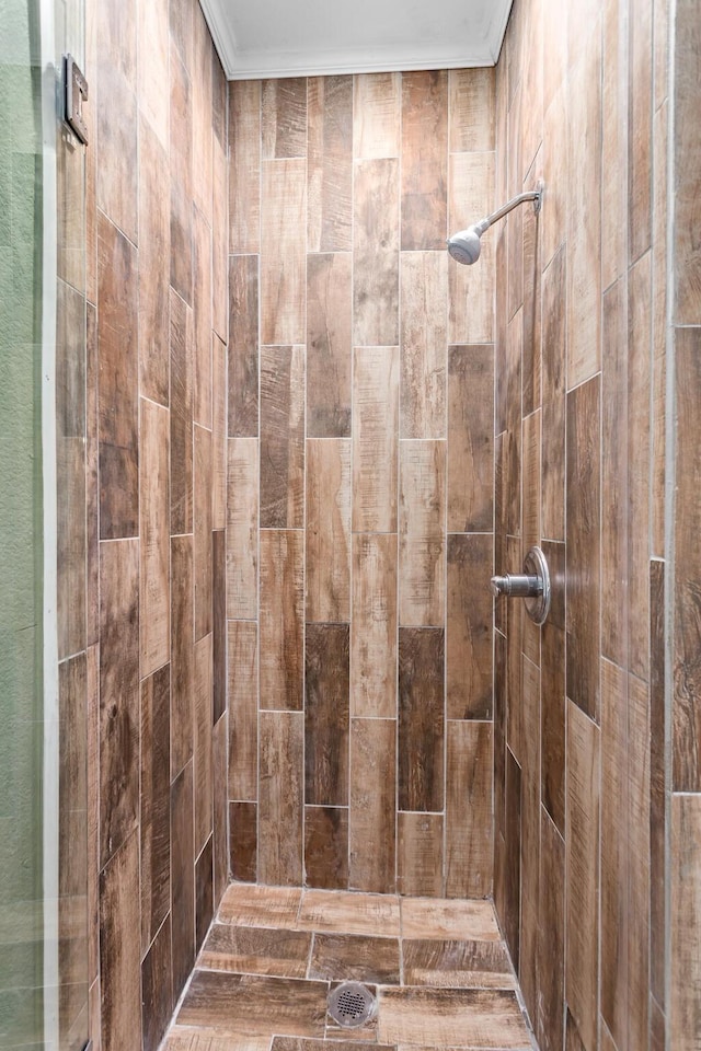 bathroom featuring tiled shower and ornamental molding