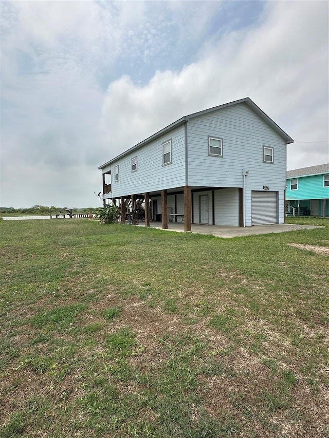 rear view of house featuring a lawn and a garage