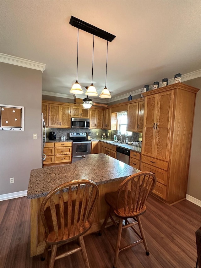 kitchen featuring decorative light fixtures, dark wood-type flooring, crown molding, and appliances with stainless steel finishes