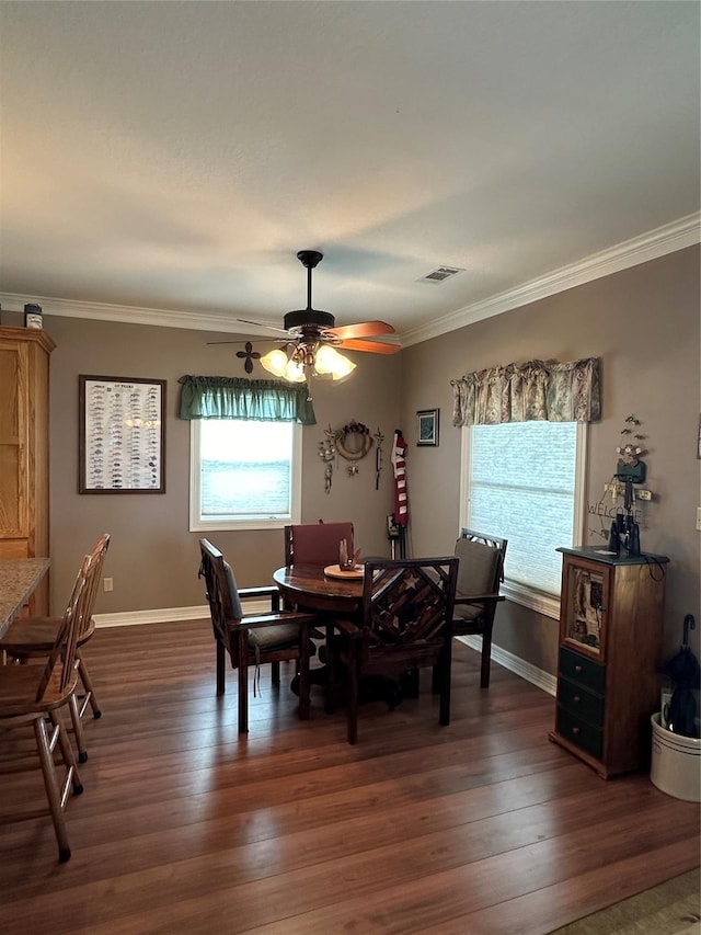 dining area with ceiling fan, plenty of natural light, ornamental molding, and dark hardwood / wood-style floors