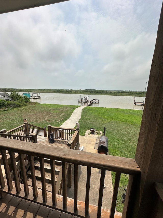 deck featuring a water view, an outdoor fire pit, and a lawn