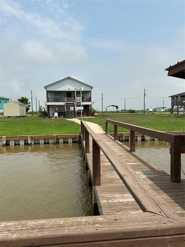 view of dock featuring a lawn and a water view