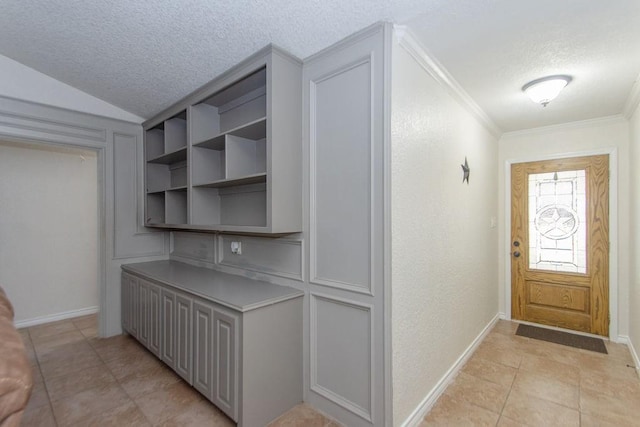 tiled entrance foyer featuring ornamental molding and a textured ceiling