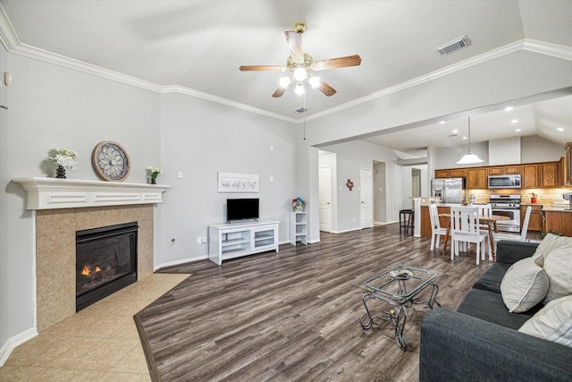 living room with lofted ceiling, a tile fireplace, and ornamental molding