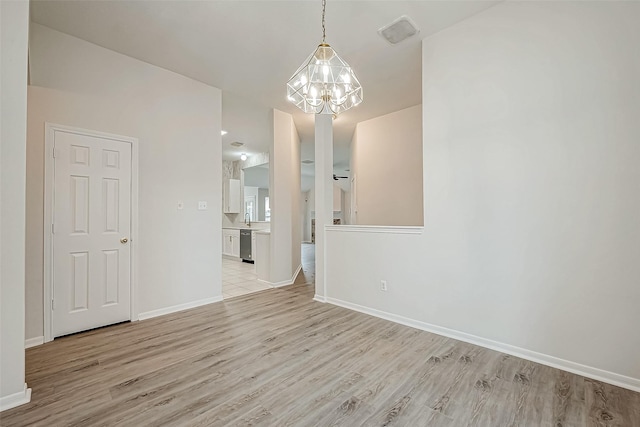 empty room with sink, a chandelier, and light hardwood / wood-style flooring