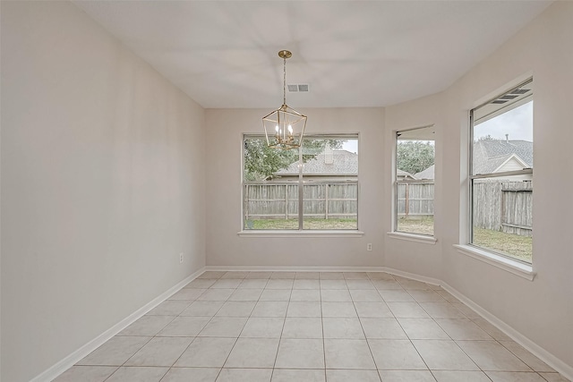 tiled spare room featuring an inviting chandelier and a wealth of natural light