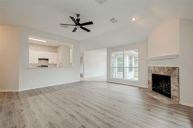 unfurnished living room featuring ceiling fan, light hardwood / wood-style flooring, and a high end fireplace