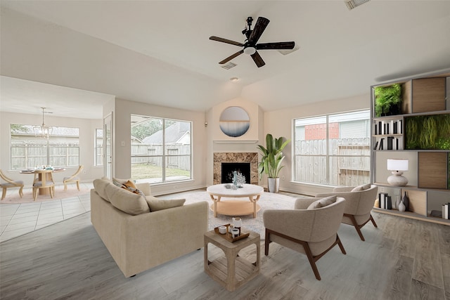 living room with ceiling fan, a wealth of natural light, hardwood / wood-style floors, and a high end fireplace