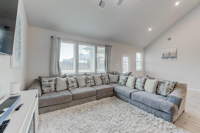 living room featuring vaulted ceiling, light wood-type flooring, ceiling fan, and plenty of natural light