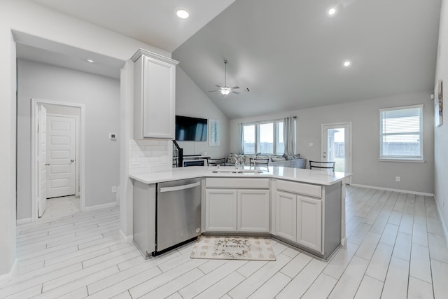 kitchen featuring kitchen peninsula, ceiling fan, sink, stainless steel dishwasher, and backsplash