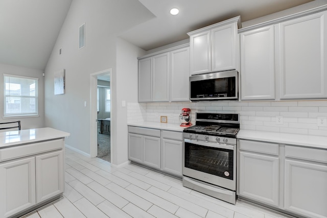 kitchen with lofted ceiling, stainless steel appliances, and tasteful backsplash