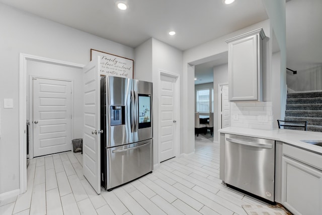 kitchen with appliances with stainless steel finishes, white cabinets, and backsplash