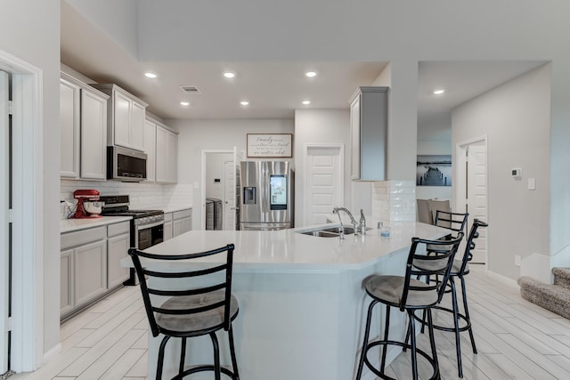 kitchen with appliances with stainless steel finishes, gray cabinetry, sink, and kitchen peninsula