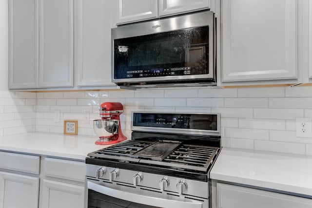 kitchen with stainless steel appliances, white cabinets, and tasteful backsplash