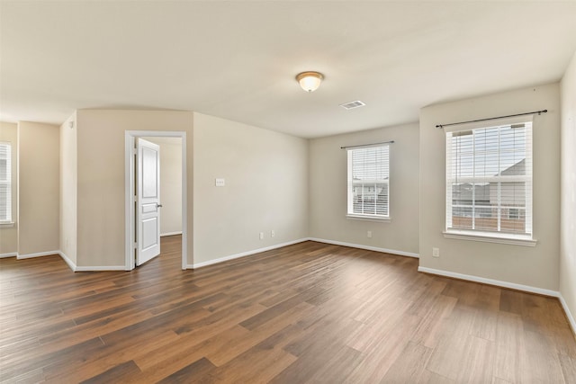 spare room with dark hardwood / wood-style flooring and plenty of natural light