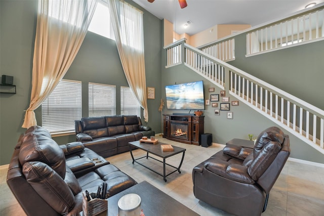 living room featuring ceiling fan, light tile patterned flooring, a towering ceiling, and a wealth of natural light