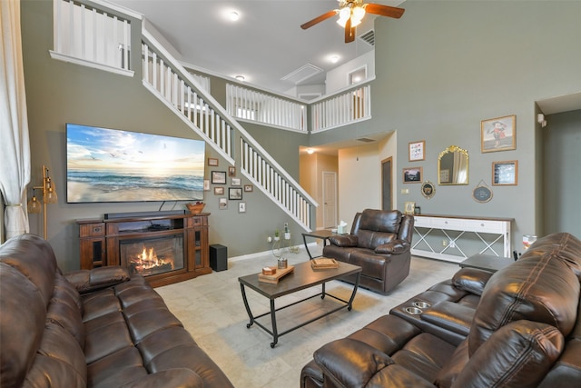 living room featuring a towering ceiling, a fireplace, and ceiling fan