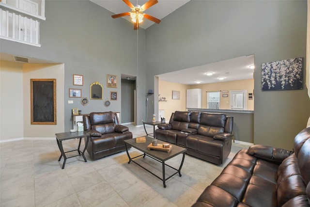 living room featuring a towering ceiling, light tile patterned flooring, and ceiling fan