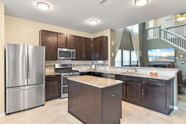 kitchen featuring sink, a kitchen island, dark brown cabinets, and appliances with stainless steel finishes