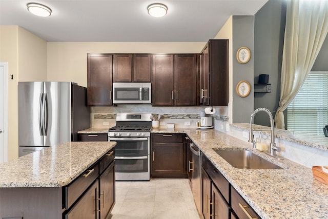 kitchen featuring light stone countertops, sink, appliances with stainless steel finishes, light tile patterned flooring, and dark brown cabinetry