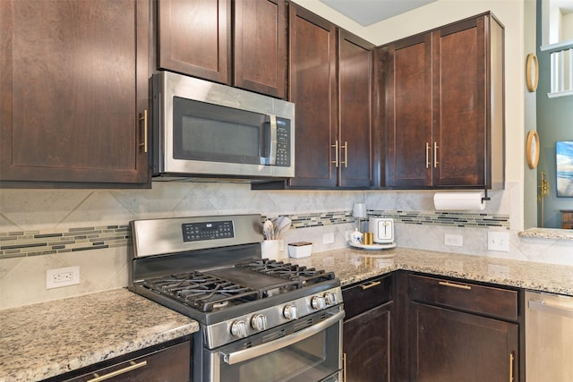 kitchen featuring light stone countertops, backsplash, dark brown cabinets, and appliances with stainless steel finishes