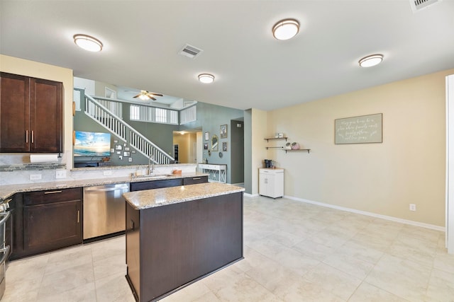 kitchen featuring light stone countertops, dishwasher, a kitchen island, ceiling fan, and sink