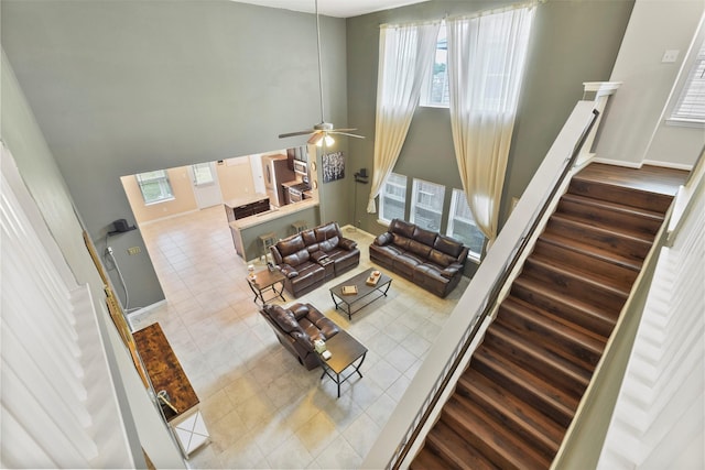 living room featuring a towering ceiling, ceiling fan, light tile patterned floors, and a wealth of natural light