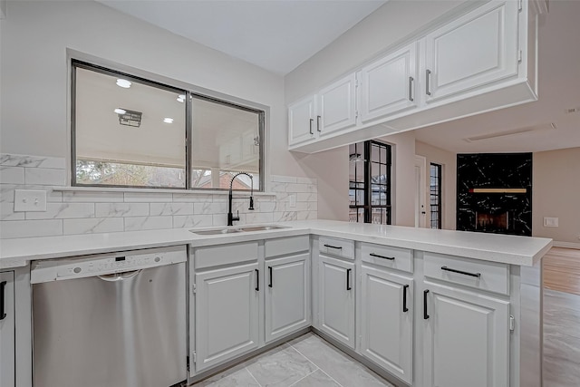 kitchen featuring white cabinets, stainless steel dishwasher, kitchen peninsula, and sink