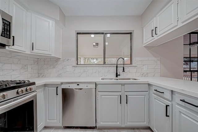 kitchen featuring white cabinets, stainless steel appliances, decorative backsplash, and sink