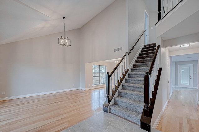 staircase featuring a notable chandelier, high vaulted ceiling, and wood-type flooring