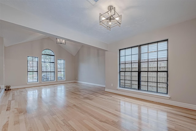 unfurnished living room with an inviting chandelier, light hardwood / wood-style flooring, and a healthy amount of sunlight