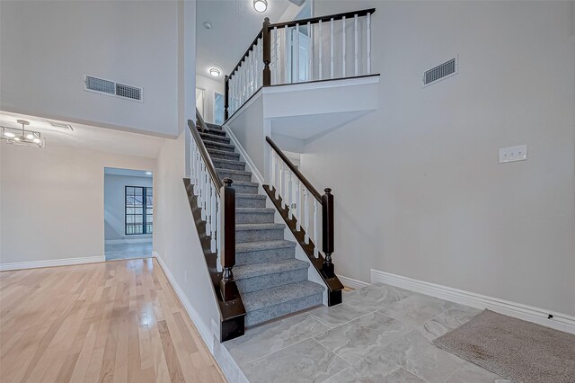 stairway with a notable chandelier and a towering ceiling