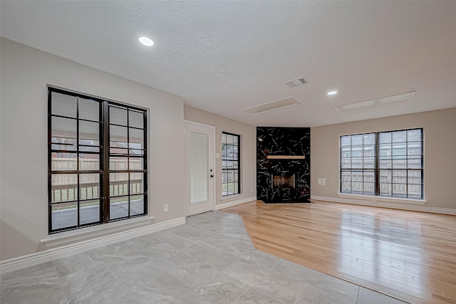 unfurnished living room featuring a textured ceiling and a high end fireplace